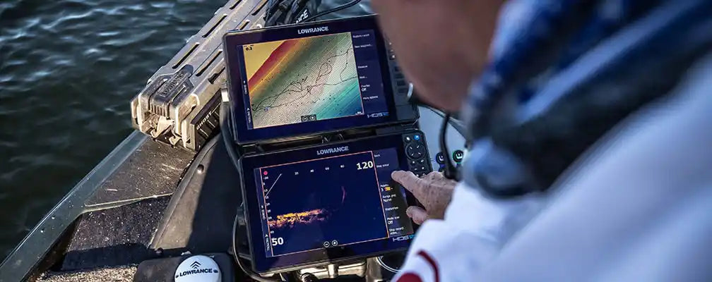 angler using lowrance fish finders on bow of walleye boat