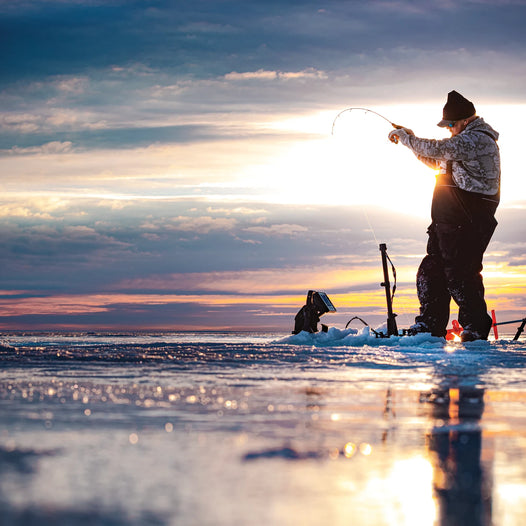 guy out ice fishing with sun and clouds in background