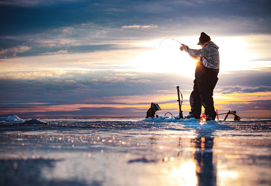 guy out ice fishing with sun and clouds in background